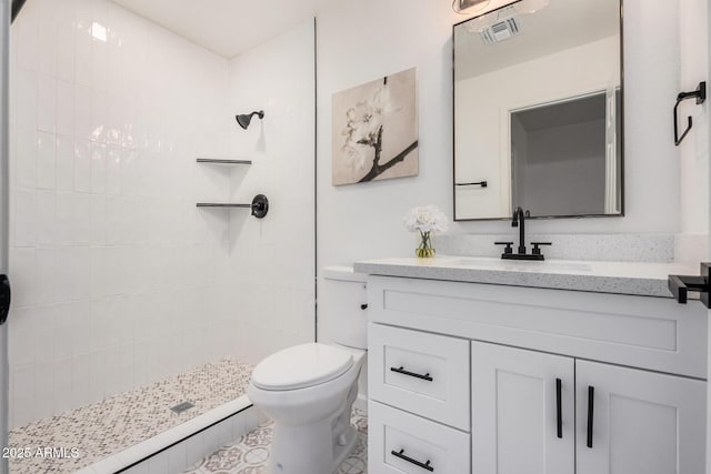 bathroom featuring vanity, toilet, and a tile shower