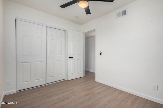 unfurnished bedroom with ceiling fan, light wood-type flooring, and a closet