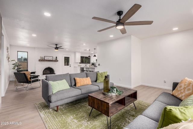 living room featuring ceiling fan, a fireplace, and light hardwood / wood-style floors