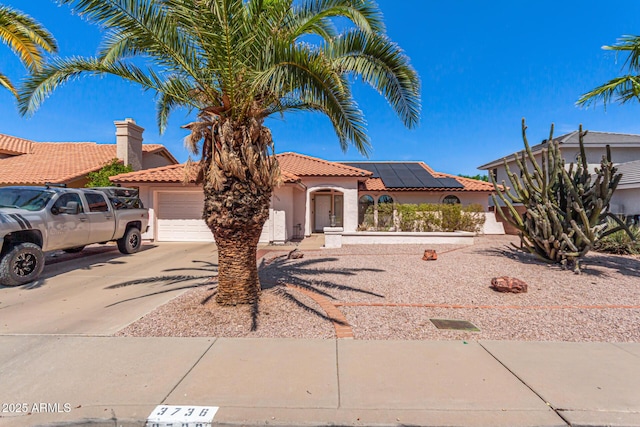 view of front of property featuring a tile roof, concrete driveway, stucco siding, roof mounted solar panels, and a garage