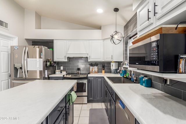 kitchen with a sink, white cabinetry, appliances with stainless steel finishes, light tile patterned floors, and custom range hood