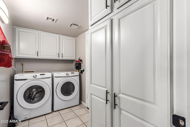 washroom featuring washing machine and clothes dryer, light tile patterned flooring, cabinet space, and visible vents