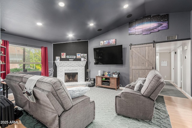 living area featuring recessed lighting, baseboards, a barn door, a brick fireplace, and wood finished floors
