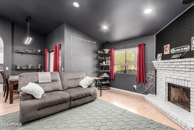living room with recessed lighting, arched walkways, a fireplace, and wood finished floors