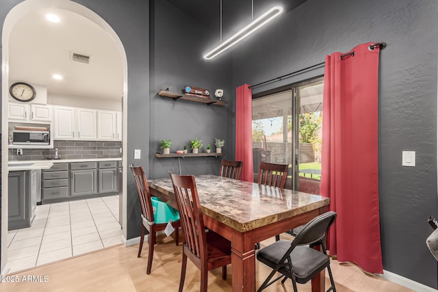 dining room with baseboards, visible vents, arched walkways, and light tile patterned floors
