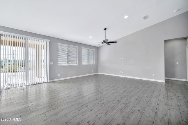 unfurnished room featuring ceiling fan, a healthy amount of sunlight, vaulted ceiling, and light hardwood / wood-style flooring