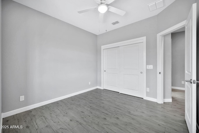 unfurnished bedroom with ceiling fan, wood-type flooring, and a closet