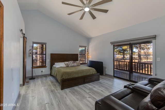 bedroom featuring light hardwood / wood-style flooring, ceiling fan, access to exterior, high vaulted ceiling, and a barn door