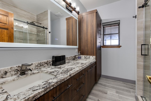 bathroom with walk in shower, vanity, and hardwood / wood-style floors