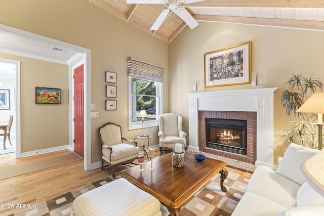 sitting room featuring light wood-type flooring, a brick fireplace, ceiling fan, wooden ceiling, and vaulted ceiling with beams