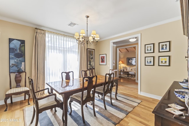 dining room with light hardwood / wood-style flooring, ornamental molding, and an inviting chandelier