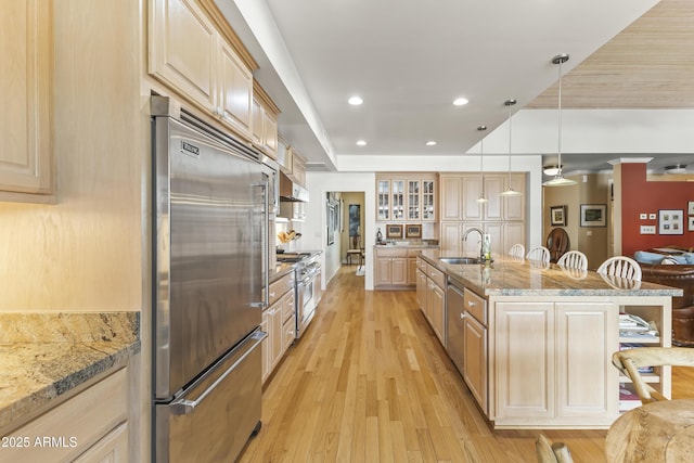 kitchen with light brown cabinets, high end appliances, and hanging light fixtures