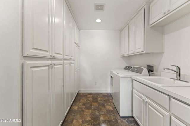 clothes washing area with separate washer and dryer, sink, and cabinets