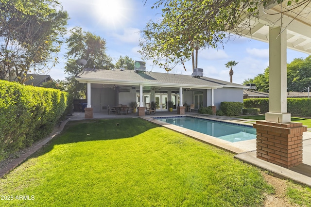 rear view of house with a fenced in pool, a patio area, ceiling fan, and a yard