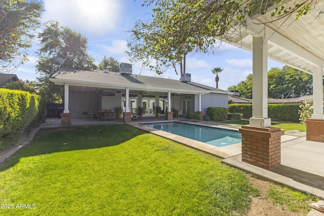 rear view of property featuring a yard, a fenced in pool, ceiling fan, and a patio area