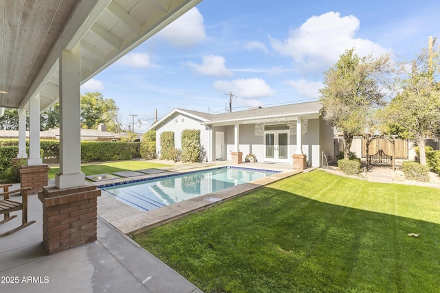 view of swimming pool with a yard and french doors