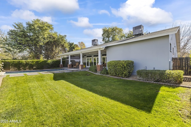 rear view of house featuring a patio, a fenced in pool, a lawn, and central air condition unit