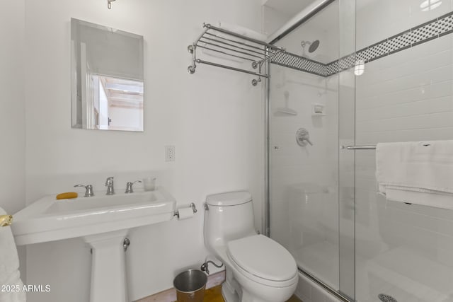 bathroom featuring a shower with door and toilet