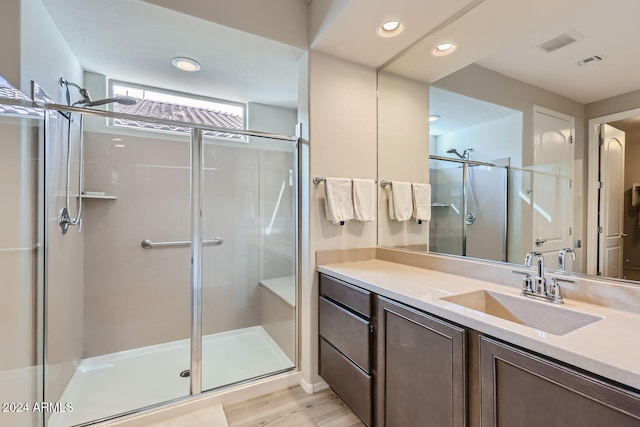 bathroom with wood-type flooring, vanity, and a shower with shower door