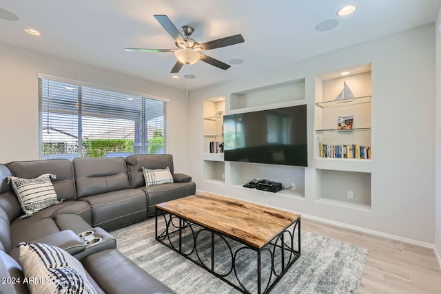 living room featuring built in features, light wood-type flooring, and ceiling fan