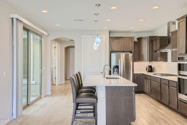 kitchen featuring hanging light fixtures, sink, a center island with sink, appliances with stainless steel finishes, and light hardwood / wood-style floors