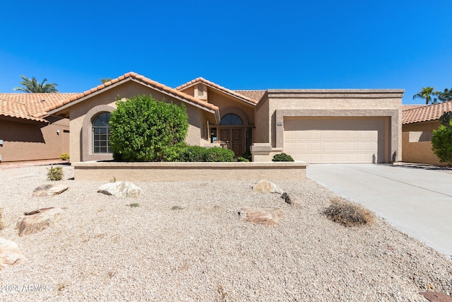 view of front of home with an attached garage, a tiled roof, concrete driveway, and stucco siding