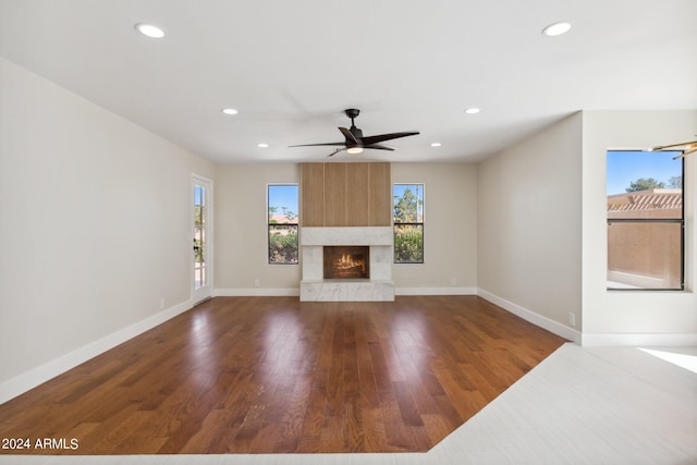 unfurnished living room featuring a fireplace, dark hardwood / wood-style floors, and ceiling fan