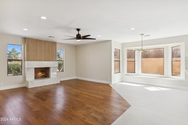 unfurnished living room with ceiling fan with notable chandelier, dark hardwood / wood-style floors, and a healthy amount of sunlight