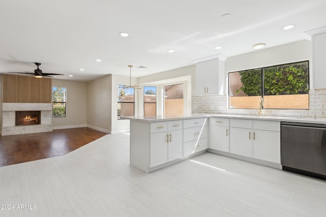 kitchen with hanging light fixtures, kitchen peninsula, dishwasher, and white cabinets