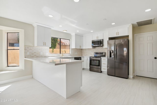 kitchen featuring tasteful backsplash, kitchen peninsula, stainless steel appliances, and white cabinets