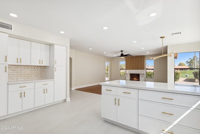 kitchen with backsplash, a large fireplace, and white cabinetry