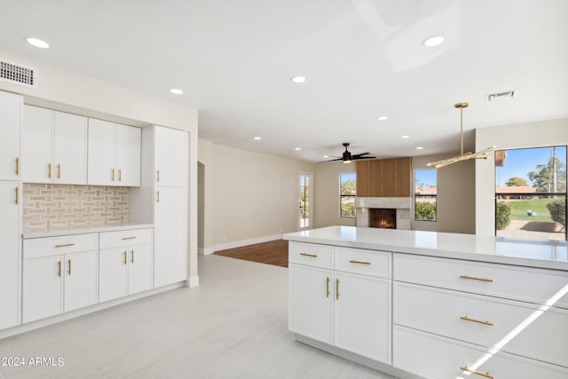 kitchen featuring tasteful backsplash, a fireplace, light countertops, a ceiling fan, and visible vents