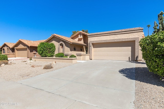 mediterranean / spanish-style house featuring a tile roof, stucco siding, an attached garage, and concrete driveway