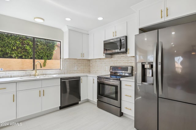 kitchen with tasteful backsplash, white cabinets, appliances with stainless steel finishes, and sink