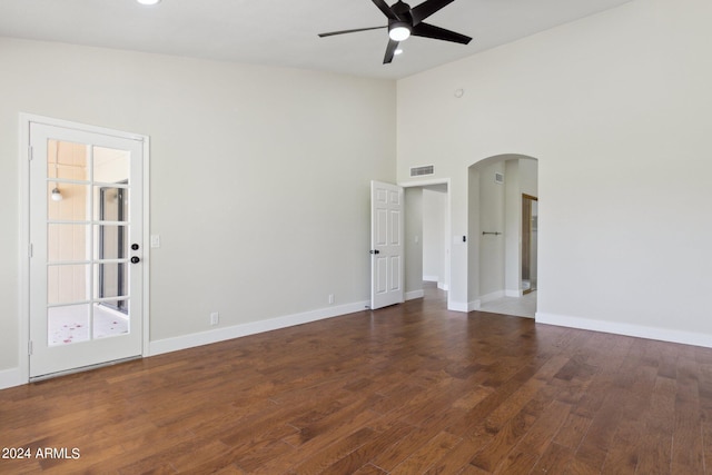 empty room with baseboards, a ceiling fan, visible vents, arched walkways, and wood finished floors