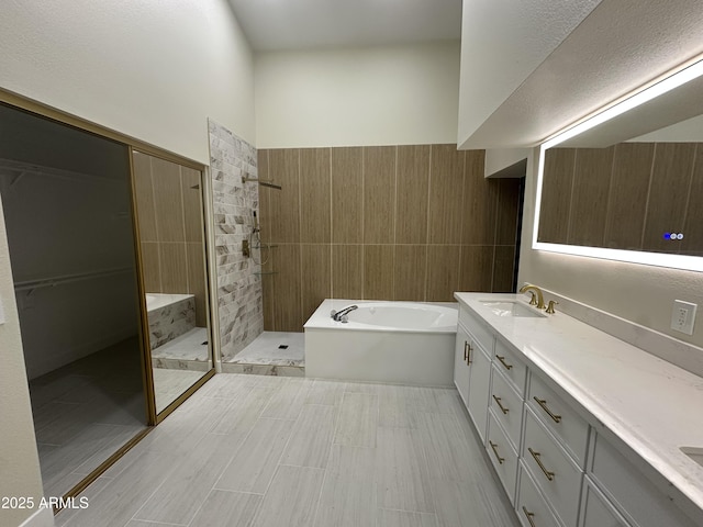 bathroom featuring vanity, a bath, tile walls, and a tile shower
