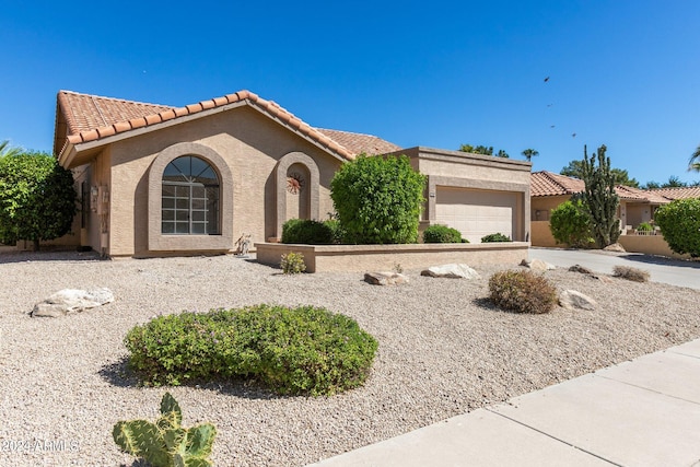 mediterranean / spanish-style home featuring an attached garage, stucco siding, and a tile roof