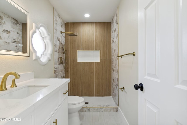 bathroom featuring a tile shower, tile patterned floors, vanity, and toilet