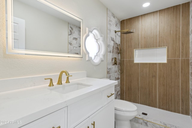 bathroom with a tile shower, vanity, and toilet