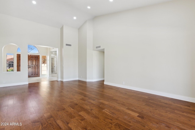 unfurnished living room featuring high vaulted ceiling and dark hardwood / wood-style flooring