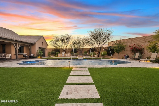 pool at dusk with pool water feature, an in ground hot tub, a yard, and a patio