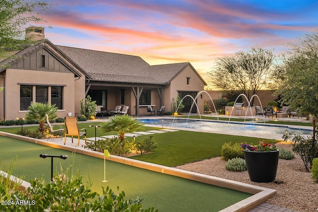 pool at dusk featuring a patio area and pool water feature