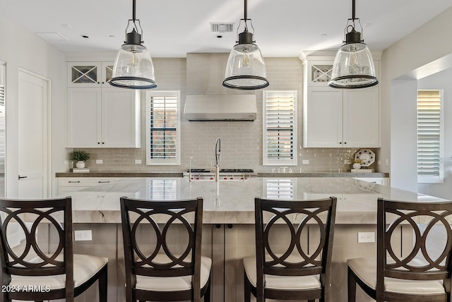 kitchen featuring decorative light fixtures, light stone counters, and white cabinetry