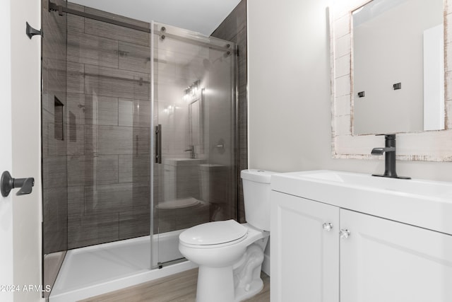 bathroom with vanity, wood-type flooring, a shower with shower door, and toilet