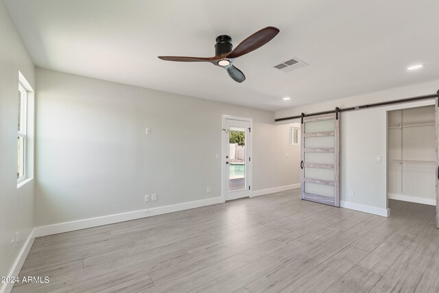 empty room with light wood-type flooring, ceiling fan, and a healthy amount of sunlight