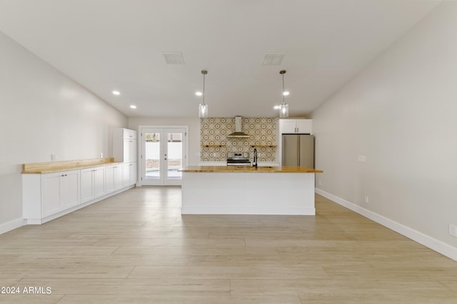 kitchen featuring appliances with stainless steel finishes, backsplash, decorative light fixtures, french doors, and wall chimney exhaust hood