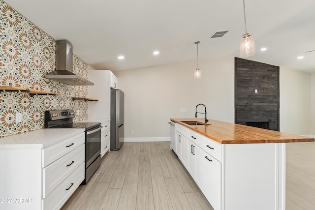 kitchen with sink, appliances with stainless steel finishes, an island with sink, pendant lighting, and wall chimney range hood