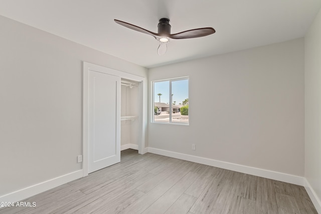 unfurnished bedroom with ceiling fan, light wood-type flooring, and a closet