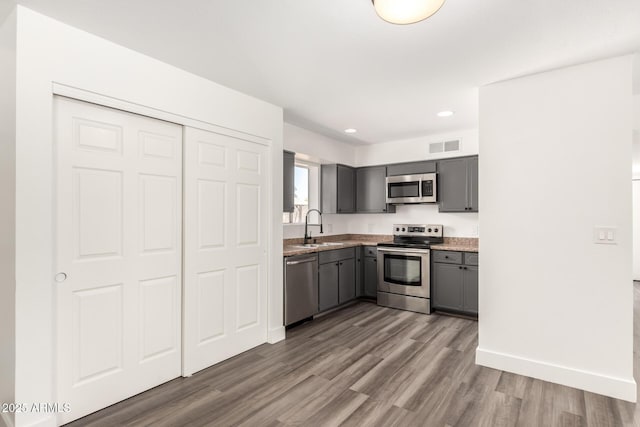 kitchen featuring a sink, gray cabinets, stainless steel appliances, wood finished floors, and visible vents