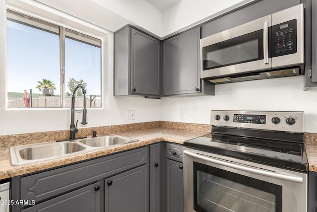 kitchen with light countertops, a sink, gray cabinets, and stainless steel appliances
